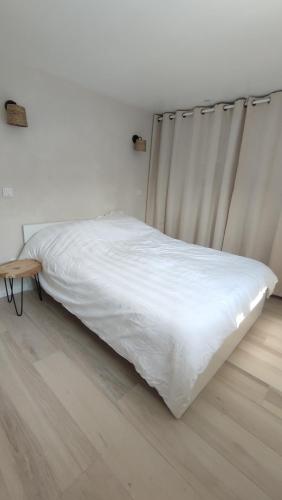 a white bed in a room with a wooden floor at La petite maison de la Drôme in Aouste-sur-Sye