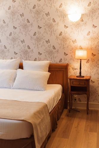 a bedroom with a bed and a table with a lamp at BRIT HOTEL Le Lion d'Or CHINON in Chinon