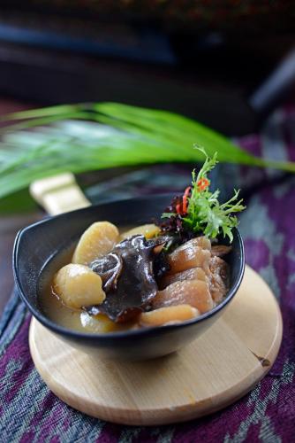 a black plate of food on a wooden table at Rumah Luwih Bali in Keramas