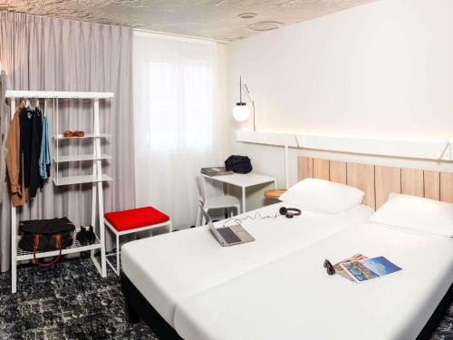 a hotel room with two beds and a desk at Ibis Pontarlier in Pontarlier