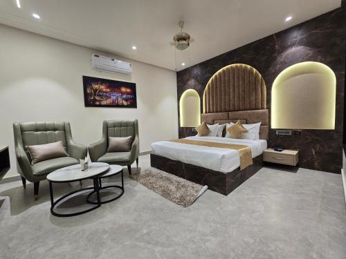 a bedroom with a bed and two chairs and a table at Hotel M Stayz Sirsa in Sirsa