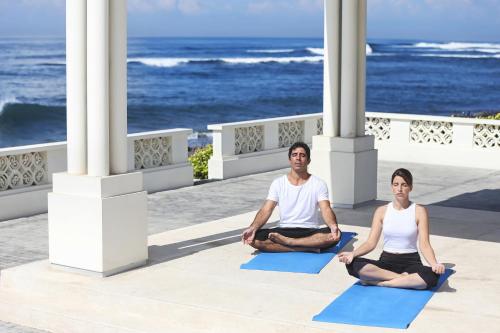a man and woman sitting in a yoga pose in front of the ocean at Rumah Luwih Bali in Keramas