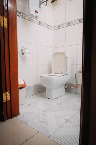 a bathroom with a toilet in a white tiled floor at Kampala Kolping Hotel in Kampala