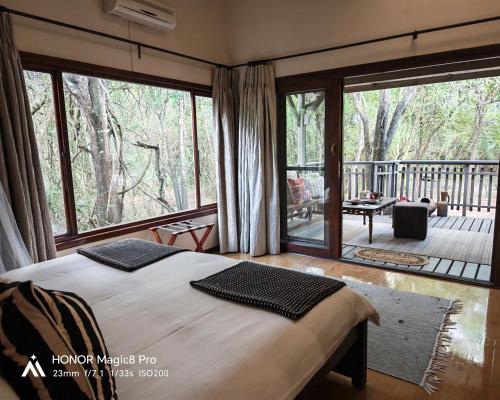 a bedroom with a bed and a large window with a deck at Thornwood in Hluhluwe