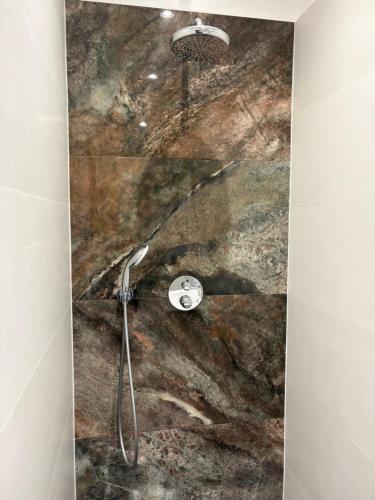 a shower in a bathroom with a marble wall at Jasmine Guest Room in Jauntīreļi