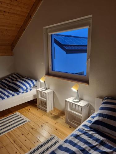 a bedroom with two beds and a large window at Domki Lawendowe in Łeba