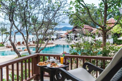 a table with a plate of food on a balcony with a pool at Chaweng Regent Beach Resort in Chaweng