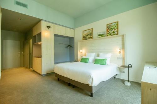 a bedroom with a large white bed with green pillows at Ysotop Hôtel Grenoble in Grenoble