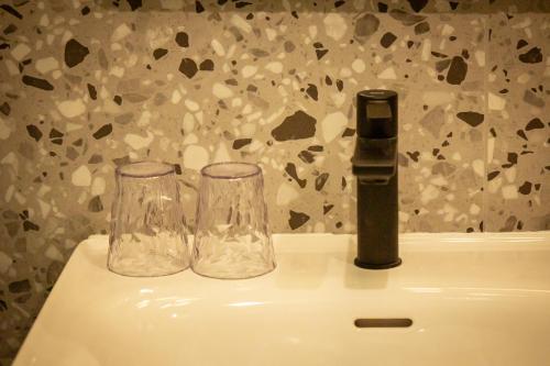 two glasses sitting on top of a sink at Ysotop Hôtel Grenoble in Grenoble