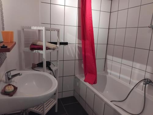 a bathroom with a white tub and a sink and a red shower curtain at Ferienhof - Rauhenberg in Wangels