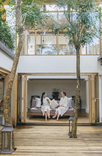 two women sitting on a couch between two trees at Chaweng Regent Beach Resort in Chaweng