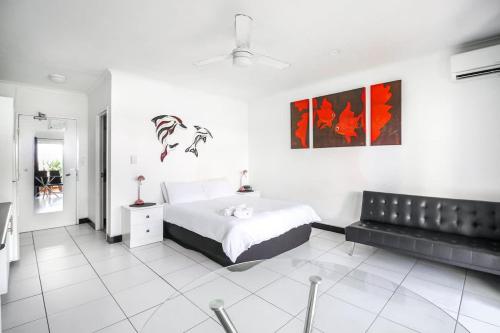 a white bedroom with a bed and a black couch at DHR U120 - The Oceana in Eimeo