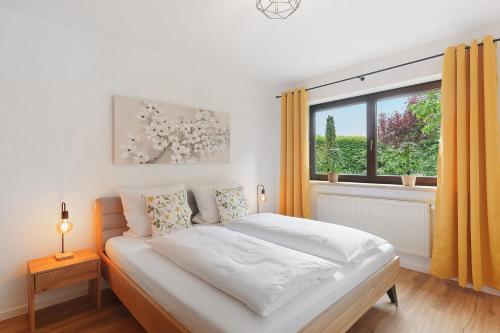 a white bedroom with a bed and a window at Apartment am Bischofsberg in Großheubach