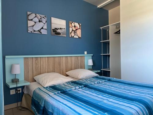 a bedroom with a bed with a blue wall at Résidence Lagrange Vacances La Grenadine in Marseillan