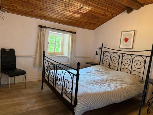 a bedroom with a bed and a chair and a window at Gîte Le Pré Doux in Ambert