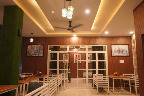 a restaurant with white chairs and tables and a ceiling at House M Lodge in Sawāi Mādhopur