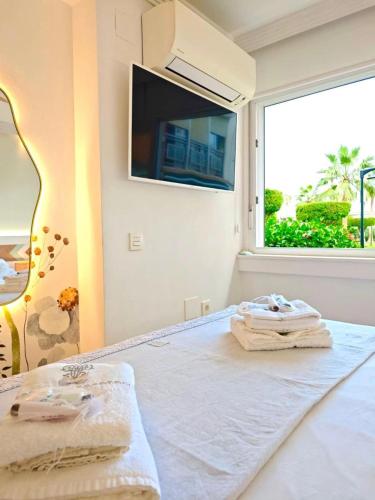a bedroom with a bed with a tv and a window at Luxury White Summer Benalmadena in Benalmádena