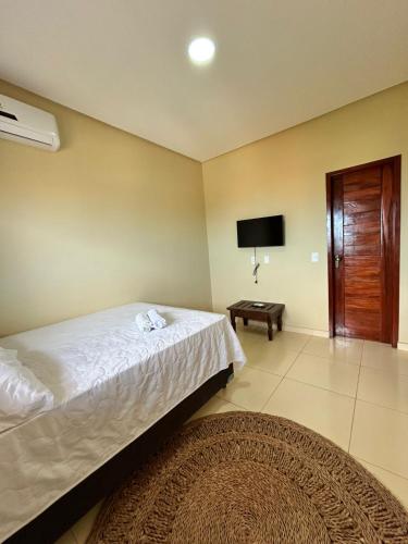 a bedroom with a bed and a tv on the wall at Pousada Makai - Cajueiro da Praia in Barra Grande