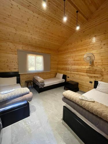 ein Zimmer mit zwei Betten in einer Holzhütte in der Unterkunft Cherry farm in Adschlun