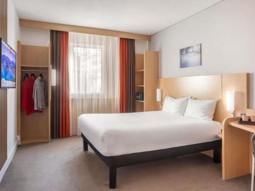 a hotel room with a large bed and a window at Ibis Lugano Paradiso in Lugano