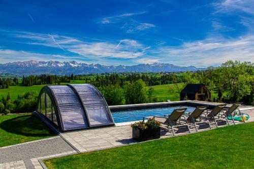 a swimming pool with chairs and a tent at Góralska Dolina II Jacuzzi & Sauna in Zakopane