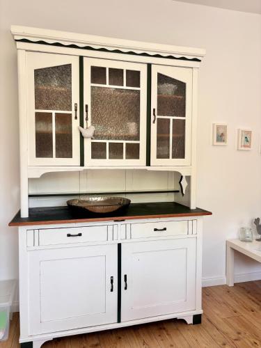 a white cabinet with a bowl on top of it at Ferienwohnung Zeitweise in Bünsdorf am Wittensee in Bünsdorf