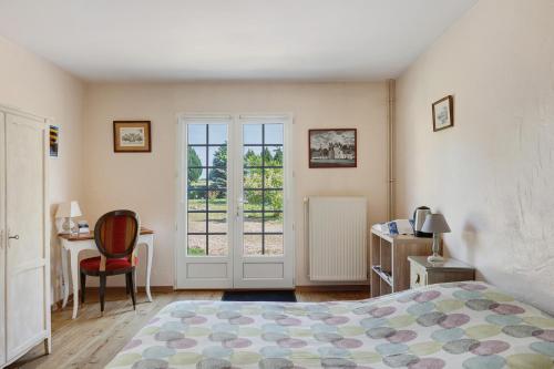 a bedroom with a bed and a desk and a window at Chambres D'hôtes La Maison Rouge - in Contres