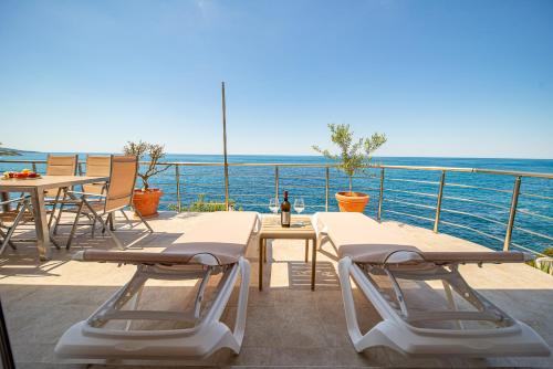 a balcony with tables and chairs and the ocean at Perfect Seaview Two-bedroom Apartment Tramontana in Dobra Voda