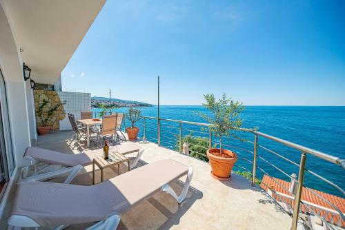 a balcony with chairs and tables and the ocean at Perfect Seaview Two-bedroom Apartment Tramontana in Dobra Voda