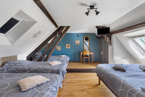 a attic room with three beds and a table at La Ferme Des Bigornes in Châtillon-sur-Indre