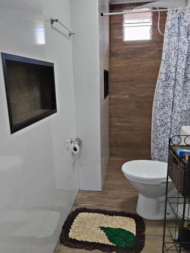 a bathroom with a toilet and a television on a wall at Espaçoso para casais in Vila Velha