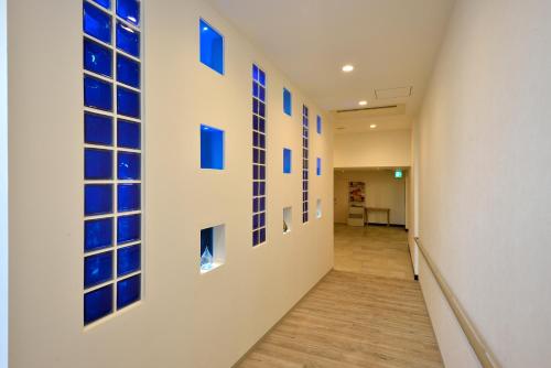 a hallway with blue glass squares on the wall at Community & Spa Naha Central Hotel in Naha