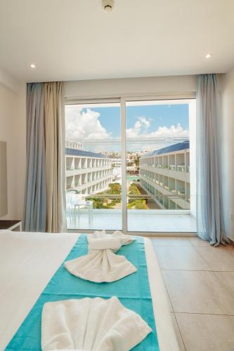 a bedroom with a large bed with a large window at Nicholas Color Hotel in Ayia Napa