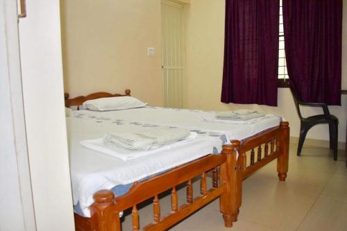 a bedroom with a wooden bed with white sheets at Sheeba's Homestay in Cochin