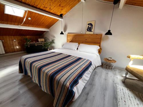 a bedroom with a large bed with a striped blanket at Atico de madera Apartamento en Rinlo, RIBADEO in Ribadeo