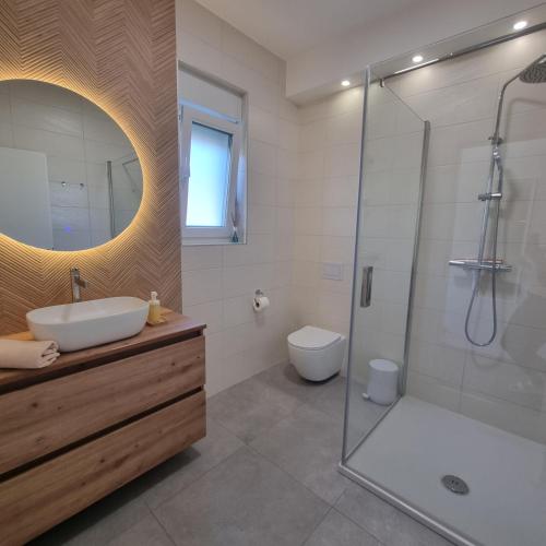 a bathroom with a sink and a shower and a toilet at Apartman Zalar in Lopar