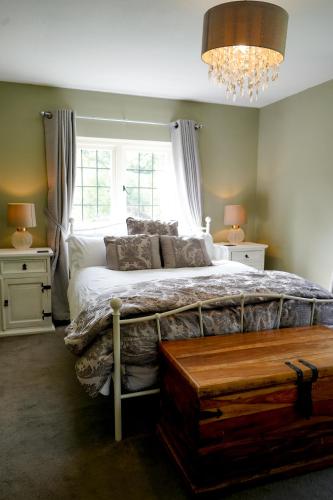 a bedroom with a large bed and a chandelier at Edwardian Cottage in beautiful surroundings with hot tub in Slinfold
