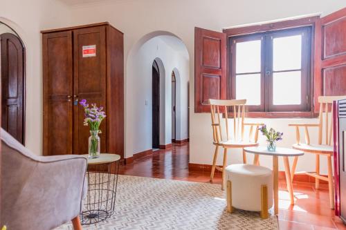 a living room with chairs and tables and a window at Foral Guest House in Óbidos