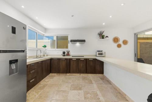 a kitchen with white walls and wooden cabinets at Tulum Paradise - Private Pool & Rooftop Deck in Tulum