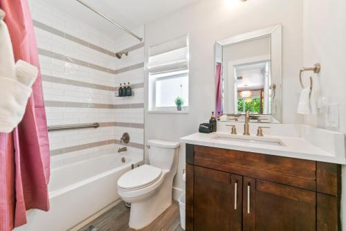 a bathroom with a white toilet and a sink and a tub at King Suite, Private Beach Path, Pool & Hot Tub in Boca Raton