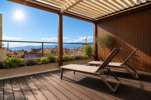 a deck with a chair and a bench on a balcony at Boutique Hotel OPERA in Rijeka