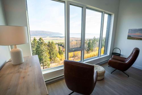 a room with a table and chairs and large windows at 411 - Luxury Condo - Incredible View & Pool in Baie-Saint-Paul