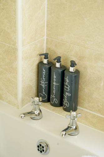 two black bottles ofodorizers sitting on a bathroom sink at Edwardian Cottage in beautiful surroundings with hot tub in Slinfold