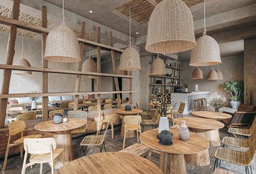 a restaurant with wooden tables and chairs and pendant lights at Nordic Vida Hotel in Cuxhaven