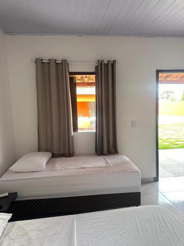 a bedroom with a bed and a window with curtains at Pousada sonho real in Barreirinhas