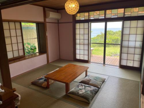 a room with a table and a bench in a room with windows at Guesthouse Papaya in Shimoda