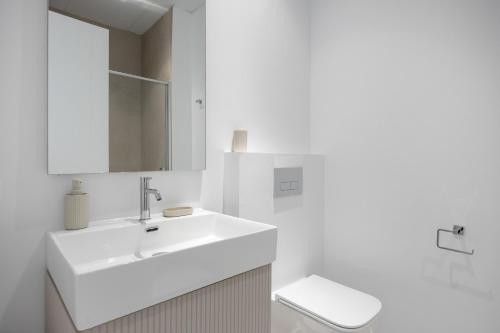 a white bathroom with a sink and a toilet at Complejo Los Drogos in Novo Sancti Petri