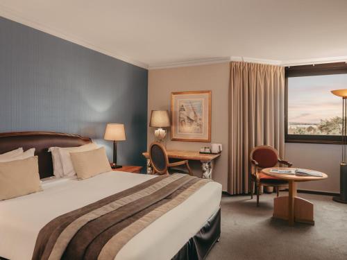a hotel room with a bed and a desk and a window at Millennium Hotel Paris Charles De Gaulle in Roissy-en-France