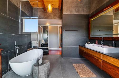 a bathroom with a tub and a sink and a mirror at Jubilee in Buffelsbaai