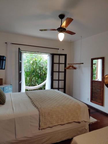a bedroom with a bed with a ceiling fan and a window at Planeta Banana Paraty in Paraty